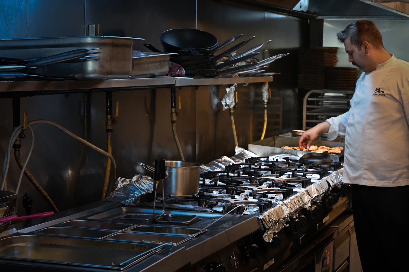 Chef cooking under a commercial kitchen hood
