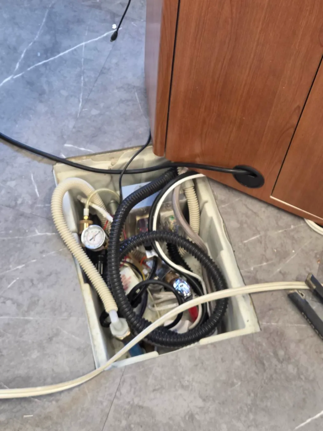 Open floor box with wiring and lines being serviced