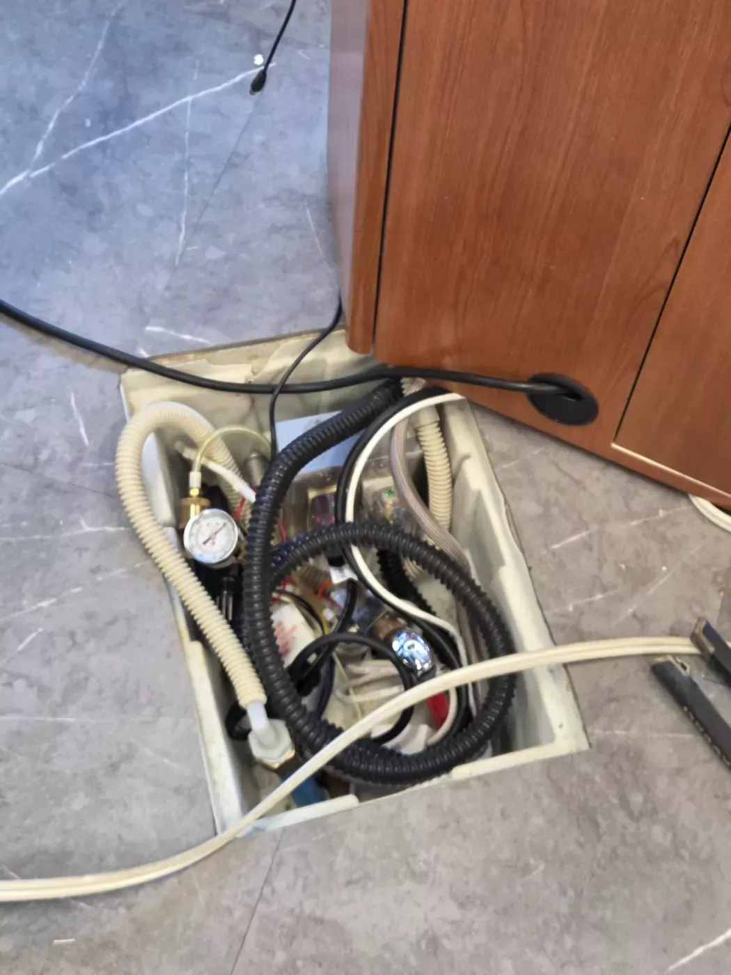 Open floor box with wiring and lines being serviced