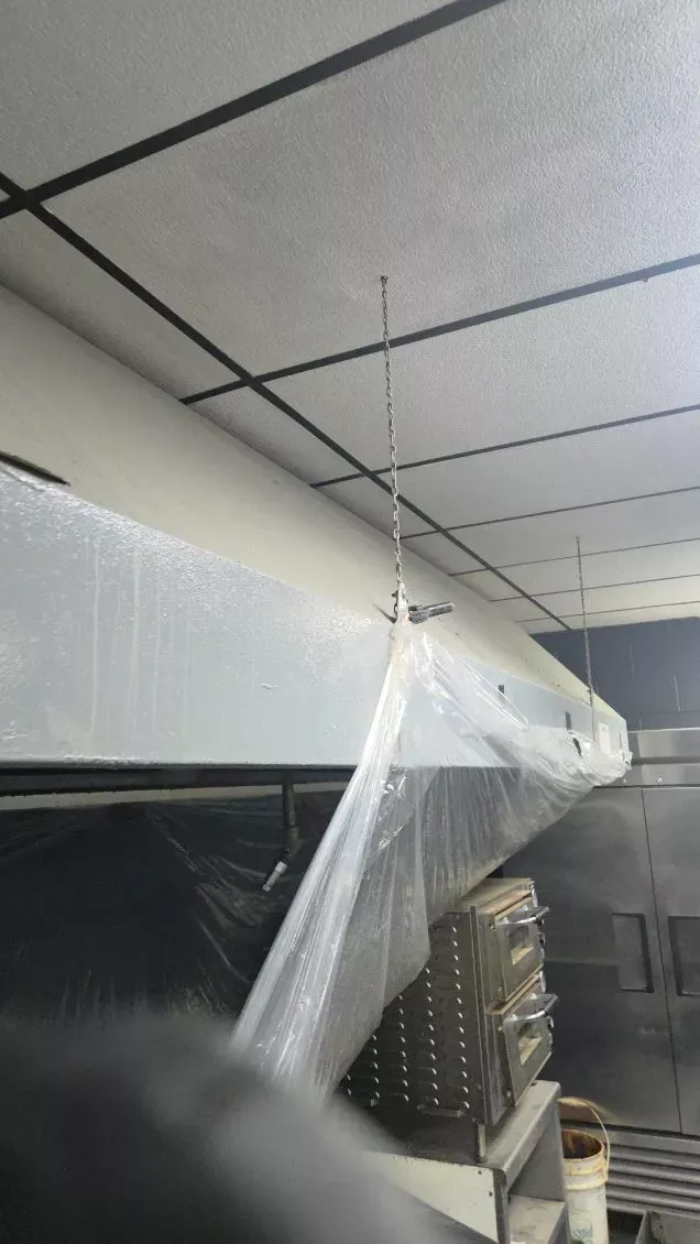 Commercial kitchen hood wrapped in plastic and ready for degreasing