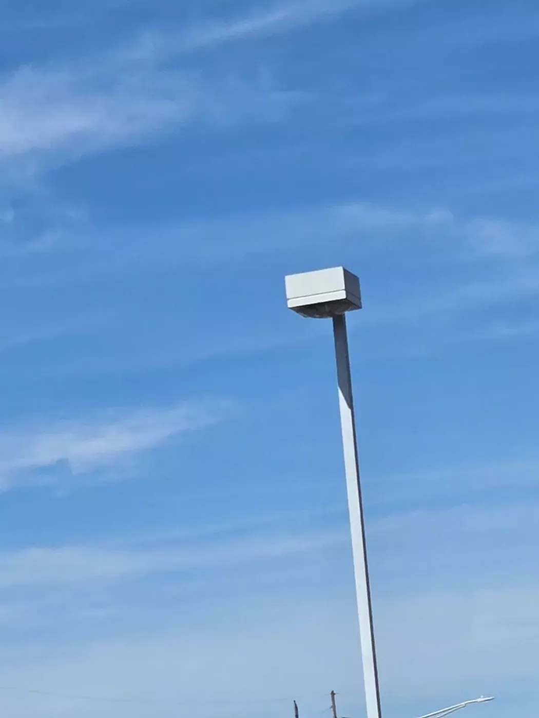 Parking lot pole light against a blue sky